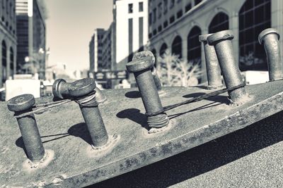 Close-up of rope tied on bollard by buildings in city