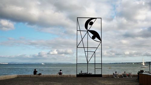 People looking at sea against sky