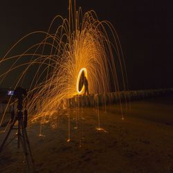 Firework display on land against sky at night