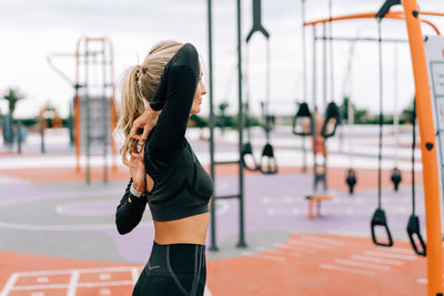 Strong athletic woman stretches her muscles after strength training.