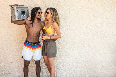 Couple with radio standing against wall