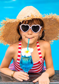 Girl with eyeglasses drinking juice in swimming pool