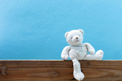 Close-up of teddy bear on table against blue wall