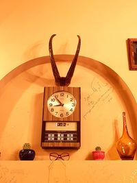 Close-up of clock on table against wall