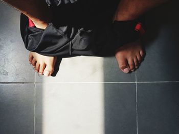 Low section of man wearing shorts standing on tiled floor