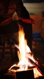 Person sitting by burning firewood