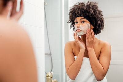 Young woman with arms raised in bathroom