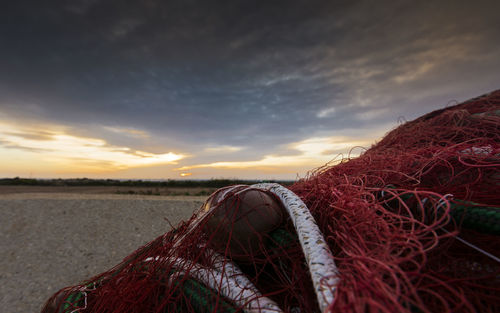 Close-up of fishing net against sky during sunset