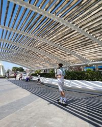 Side view of man skateboarding on footpath during sunny day