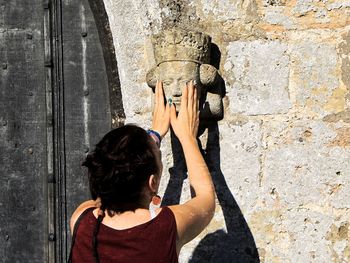 Rear view of women touching sculpture on wall