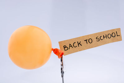 Close-up of back to school text on paper with yellow balloon against white background