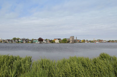 Scenic view of river by buildings against sky