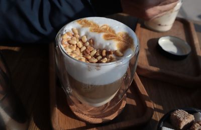 Coffee with whipped cream and pine nuts on a wooden stand.	