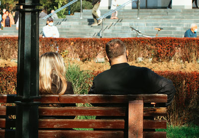 Rear view of people sitting on bench