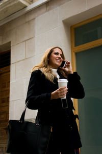 Young woman talks on her phone while walking down the street