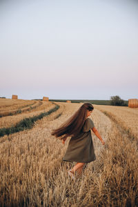 Rear view of woman standing on field against sky