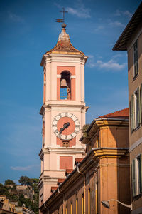 Low angle view of clock tower amidst buildings against sky