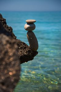 Close-up of pebbles on rock at sea shore against sky