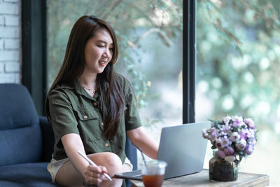 Young woman using mobile phone while sitting at home