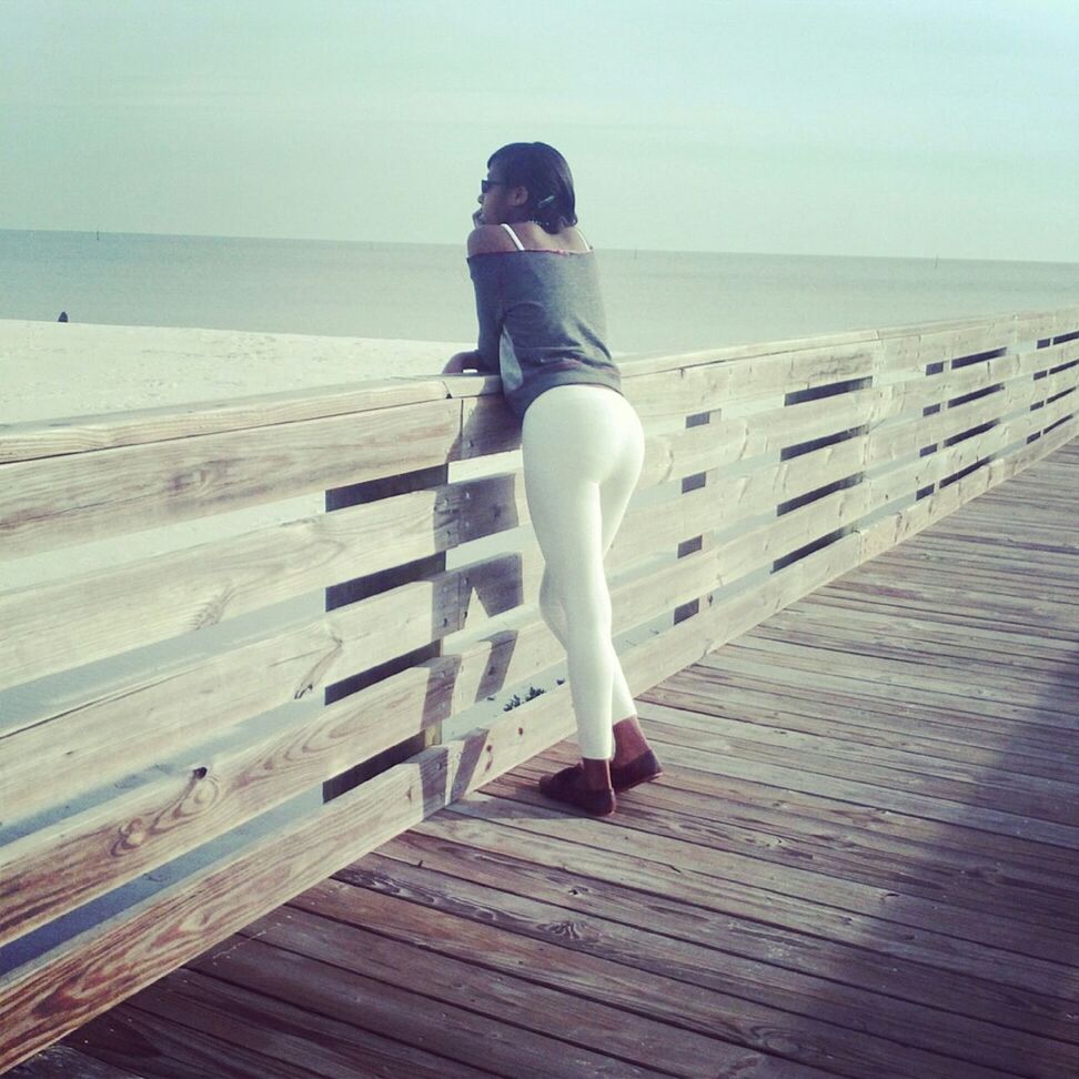 sea, horizon over water, beach, water, full length, rear view, sky, shore, tranquility, wood - material, tranquil scene, railing, standing, pier, lifestyles, sand, nature, leisure activity