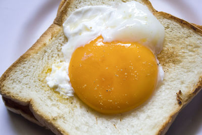 Fried egg on toast and black coffee in a glass.