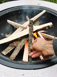 Cropped hand of man keeping wood on bonfire