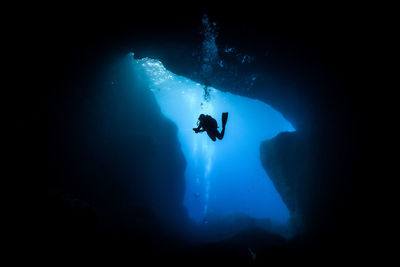 Silhouette person scuba diving undersea