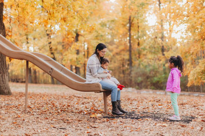 Mother and kids playing in park during autumn