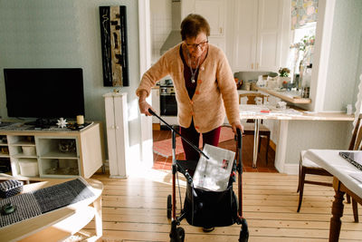 Senior woman removing newspaper with picker from basket at nursing home