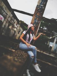 Full length of woman sitting in city against sky