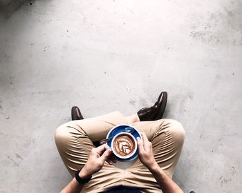 Low section of man with coffee sitting on floor