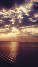 Scenic view of sea against cloudy sky at sunset