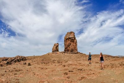 People walking on landscape against sky