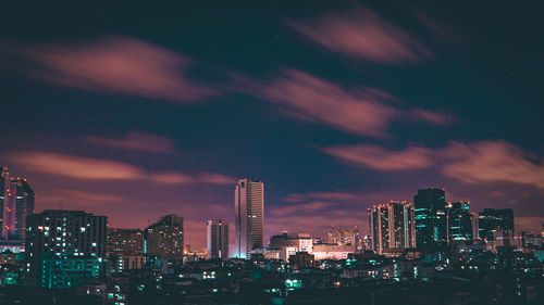 Illuminated buildings in city against sky at night