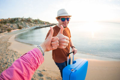 Portrait of man holding sunglasses at beach