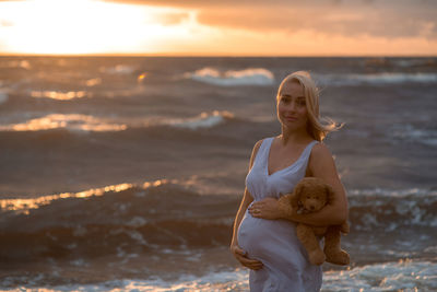 Portrait of pregnant woman standing on beach