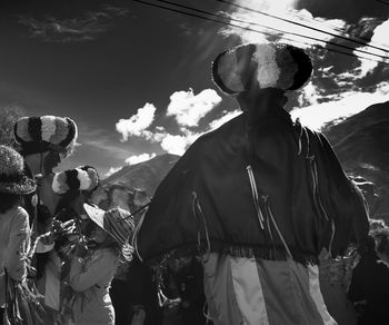 People standing by mountain against sky