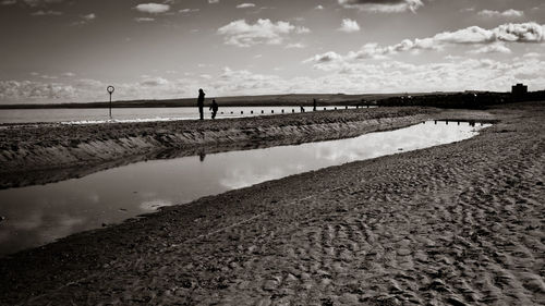 Silhouette people on beach against sky