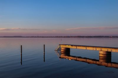 Wooden pier on lake against sky during sunset