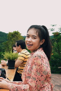 Portrait of a smiling young woman against sky