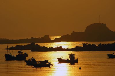Silhouette boats sailing in sea against clear sky during sunset