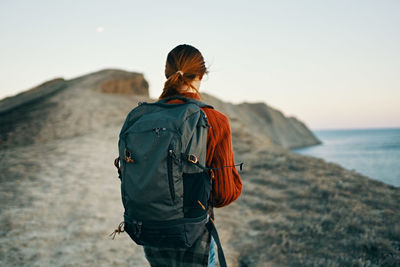 Rear view of man looking at sea shore against sky