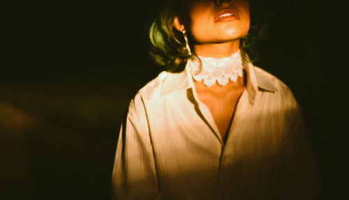 Portrait of woman standing against black background