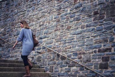Full length of woman on steps against brick wall