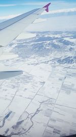 Aerial view of airplane wing over snow landscape