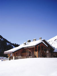 Snow covered house against clear blue sky