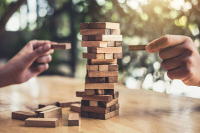 Cropped image playing with wooden toy blocks on table