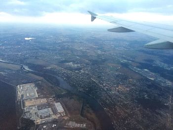 Cropped image of airplane flying over sea in city