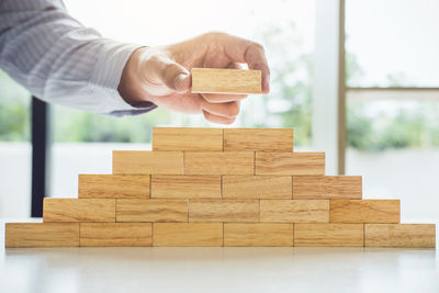 Cropped image of businessman holding toy block on table