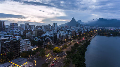 High angle view of city lit up against cloudy sky